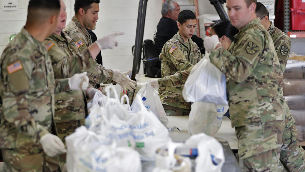 26.03.2020, USA, Mesa: Mitglieder der Nationalgarde von Arizona packen und sortieren Lebensmittel in einer Lebensmittelbank Foto: Matt York/AP/dpa +++ dpa-Bildfunk +++