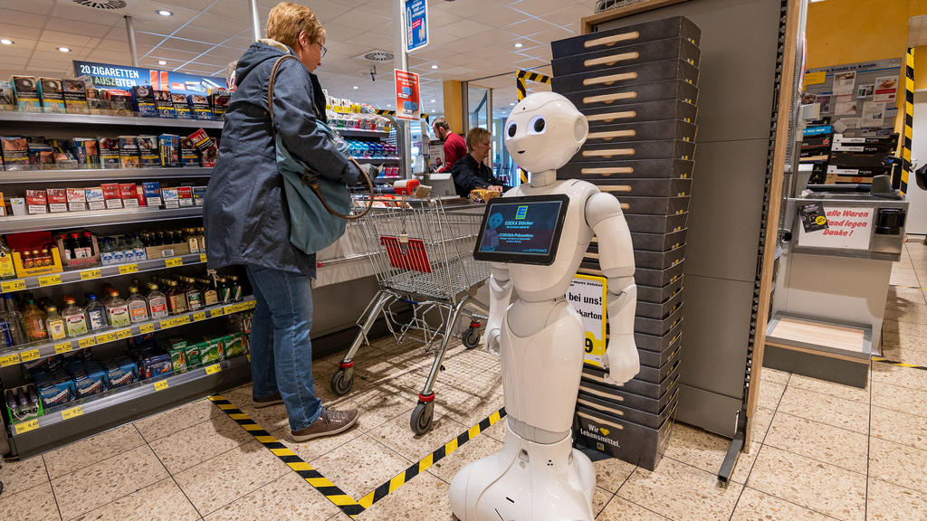 28.03.2020, Nordrhein-Westfalen, Lindlar: Pflegeroboter «Pepper» steht im Kassenbereich des Edeka-Marktes und weist Kunden darauf hin, Abstand zu halten und sich vor einer Ansteckung mit dem Coronavirus zu schützen. Außerdem wirbt er für Rücksichtnah