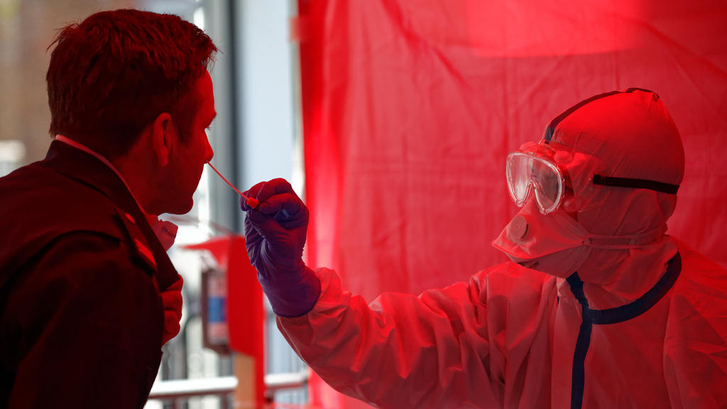 31.03.2020, Nordrhein-Westfalen, Köln: Einem Mitarbeiter der Berufsfeuerwehr Köln wird im dritten Infektionsschutzzentrum der Stadt Köln mit einem Stäbchen ein Abstrich für einen Test auf den Coronavirus entnommen. In der neu eröffneten Einrichtung i