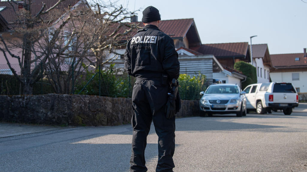 03.04.2020, Bayern, Vogtareuth: Ein Polizist steht auf einer Straße vor einem Haus in Vogtareuth, in dem drei Tote Menschen aufgefunden worden waren. Zwei tote Kinder und ihre tote Mutter haben Ermittler in einem Haus in Vogtareuth nahe Rosenheim gef