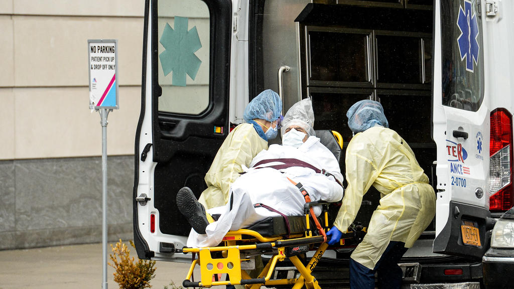 03.04.2020, USA, New York: Sanitäter transportieren einen Patienten, der sich mit dem Coronavirus infiziert hat. Der US-Bundesstaat New York gilt als eines der Epizentren der Corona-Pandemie in den USA. Mehr als 100 000 Menschen in New York haben sic