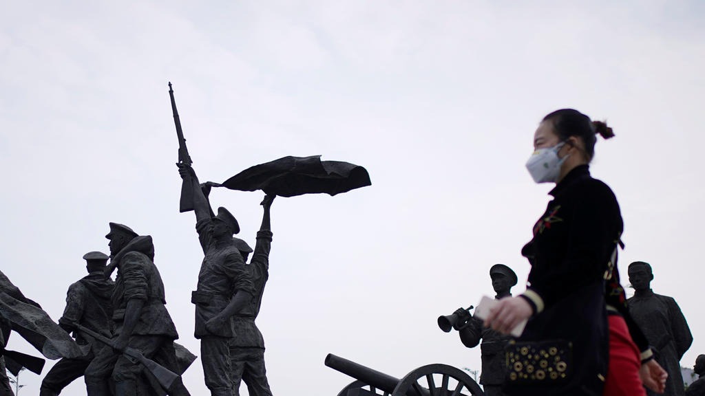 A resident wearing a face mask walks past statue symbolising Xinhai Revolution, a revolution that toppled China's last emperor in 1911, in Wuhan, Hubei province, the epicentre of China's coronavirus disease (COVID-19) outbreak, April 6, 2020. REUTERS