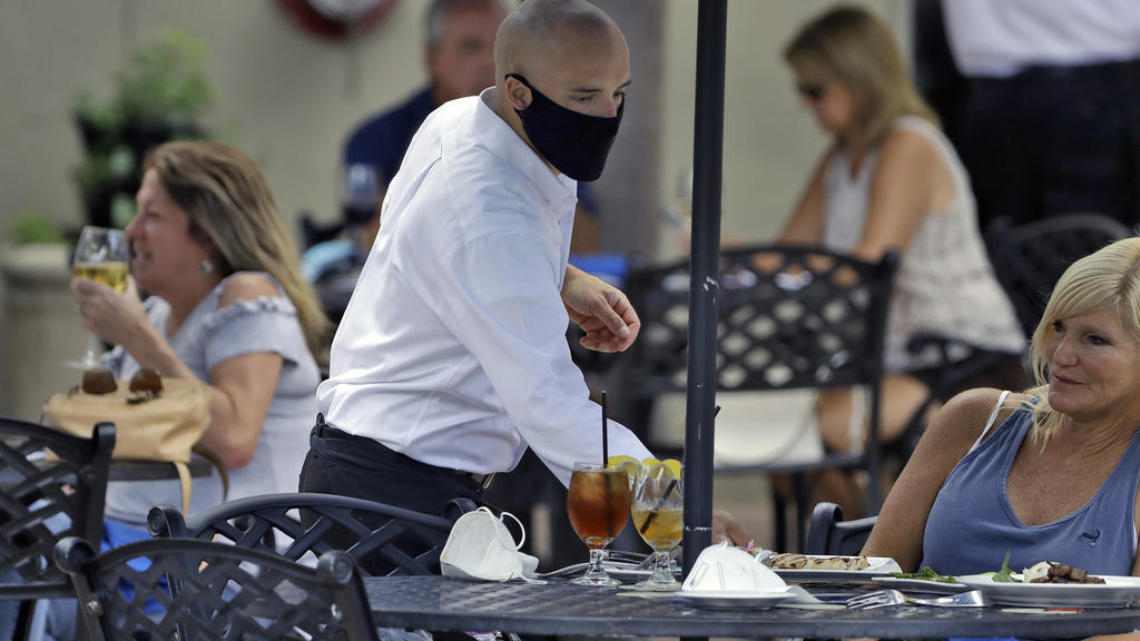 A food server at the Parkshore Grill restaurant wears a face mask while waiting for customers on Monday, May 4, 2020 in St. Petersburg, Florida. Several restaurants are reopening with a capacity of 25 as part of the Florida government. Ron DeSantis's plan to stop the