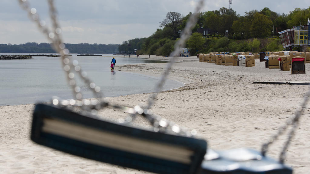 05.01.2020, Schleswig-Holstein, Kiel: Two people can be seen in the sun through a knotted swing as they walk along the Kiel-Schilksee beach. Sun and rain alternated on May 1, 2020 in Schleswig-Holstein.