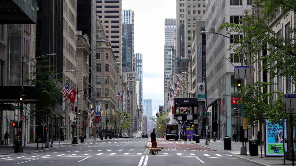 A man walks dogs across a nearly empty 5th Avenue and closed luxury retail stores, during the outbreak of the coronavirus disease (COVID-19), in Manhattan, New York city, New York, U.S., May 11, 2020. REUTERS/Mike Segar     TPX IMAGES OF THE DAY