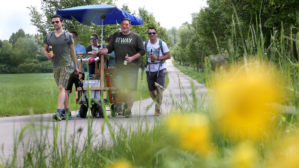 Eine Gruppe Männer ist am 25.05.2017 bei ihrer Vatertagstour mit Handwagen und einem Sonnenschirm bei Erisdorf (Baden-Württemberg) unterwegs. Foto: Thomas Warnack/dpa | Verwendung weltweit