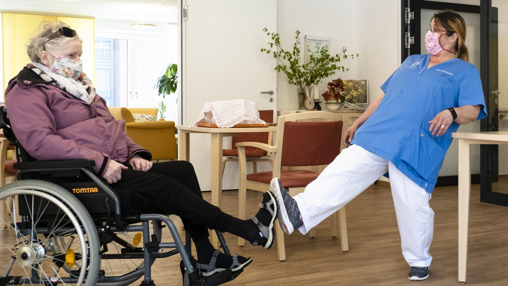 24.04.2020, Schleswig-Holstein, Kiel: Altenpflegerin Jaqueline Ackermann (r) und Bewohnerin Karin Plagemann begrüßen sich per Fuß im Kurt-Engert-Haus im Stadtteil Holtenau. In der Pflege- und Senioreneinrichtung der Stiftung Kieler Stadtkloster gilt