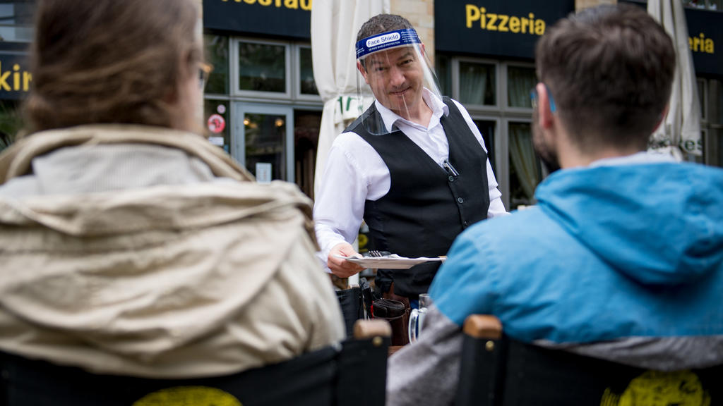 15.05.2020, Sachsen, Leipzig: Ein Kellner bedient Gäste im "Brauhaus an der Thomaskirche". Nach acht Wochen Pause starten viele Kneipen und Restaurants in Sachsen am 15.05. nach dem Lockdown. Etwas Skepsis ist noch da. Die Freude und Erleichterung üb