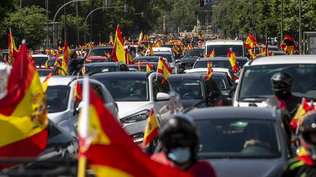 23.05.2020, Spanien, Madrid: Anhänger der rechtspopulistischen Partei Vox schwenken bei einer Demonstration die Nationalflagge von Spanien. Tausende haben bei Kundgebungen in ganz Spanien gegen die Anti-Corona-Maßnahmen den Rücktritt des sozialistisc
