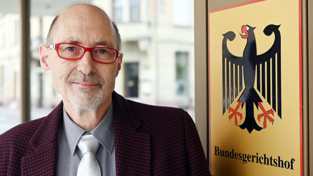ARCHIV - 05.05.2020, Baden-Württemberg, Karlsruhe: Herbert Gilbert, Kläger gegen den Autobauer VW im Dieselskandal, steht vor dem Bundesgerichtshof (BGH), vor dem Beginn seiner Verhandlung, an einem Hinweisschild mit dem Bundesadler und dem Schriftzu