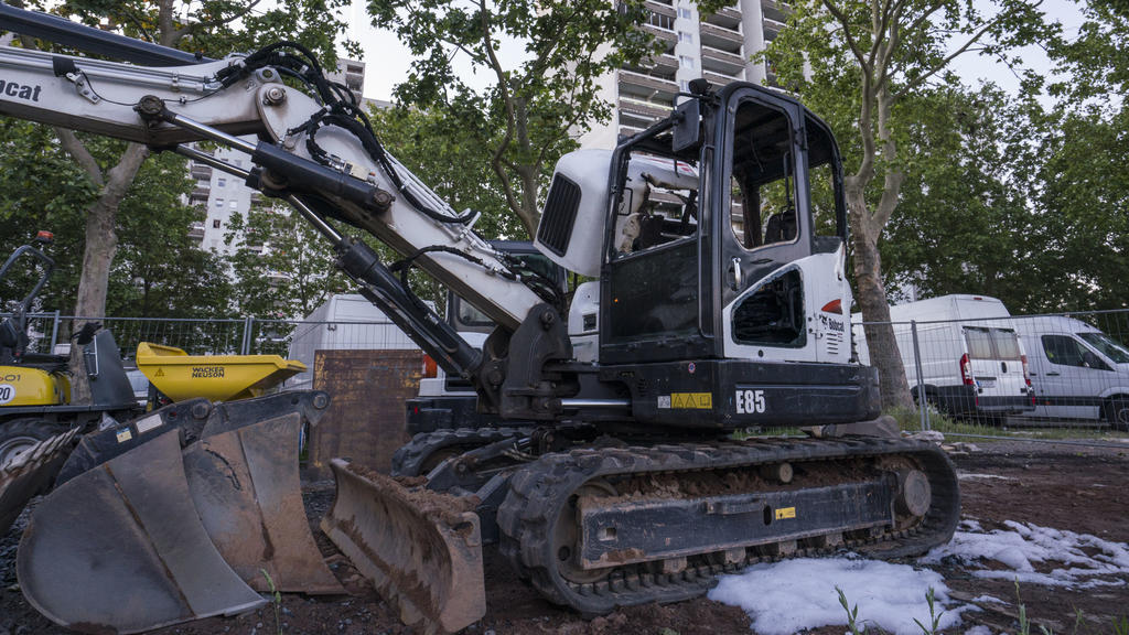 29.05.2020, Hessen, Dietzenbach: Ein ausgebrannter Bagger steht am Rande einer Hochhaussiedlung. Etwa 50 Männer haben im hessischen Dietzenbach (Landkreis Offenbach) einen Brand gelegt und anschließend die Rettungskräfte angegriffen. Polizisten und F