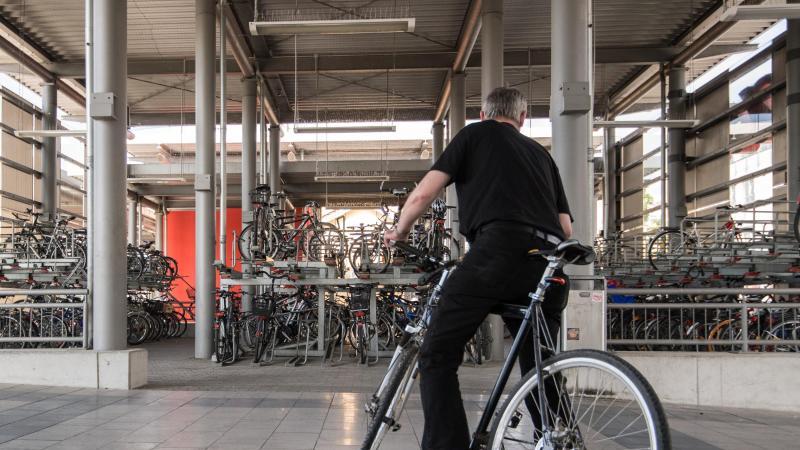 Ein Mann verlässt mit seinem Fahrrad ein Fahrradparkhaus