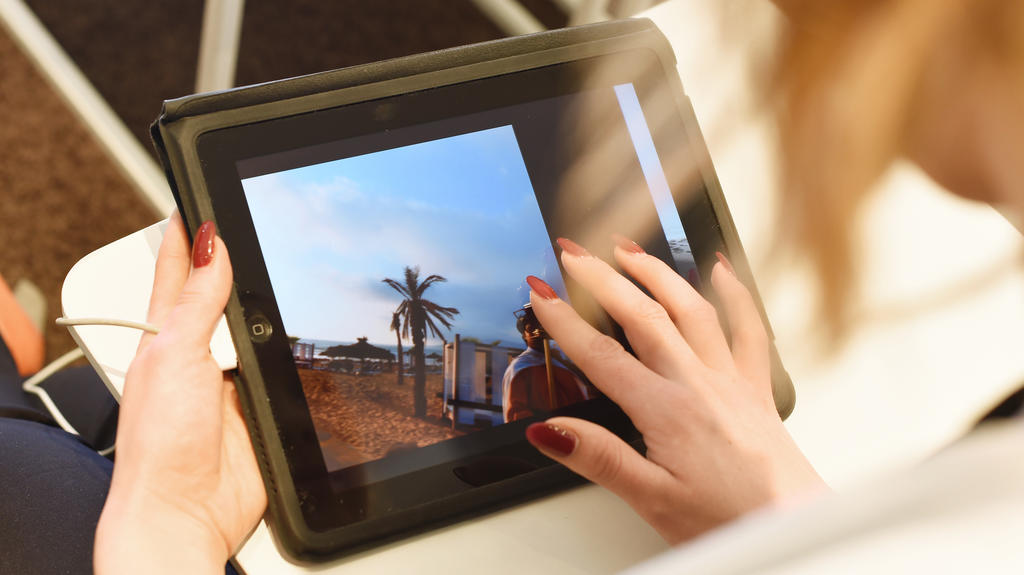Eine junge Frau schaut sich am 17.03.2015 im Reisebuero World of TUI in Berlin auf einem Tablet eine Hotelanlage an (gestellte Szene).