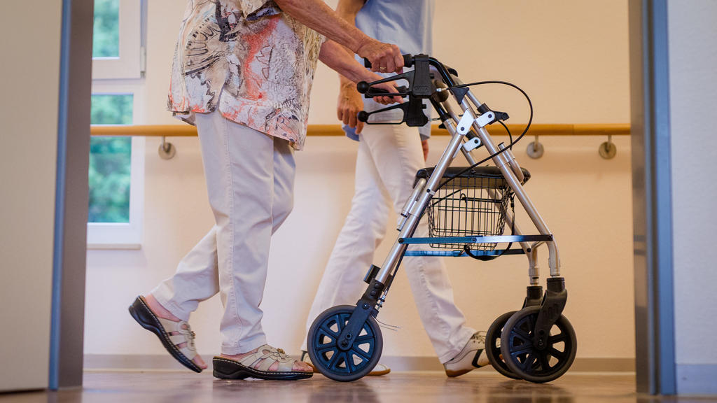 ARCHIV - 23.08.2018, Stuttgart: Eine Pflegekraft geht in einem Pflegeheim mit einer älteren Dame über einen Korridor. (zu dpa «AOK-Zahlen zur Pflege in Rheinland-Pfalz») Foto: Christoph Schmidt/dpa +++ dpa-Bildfunk +++