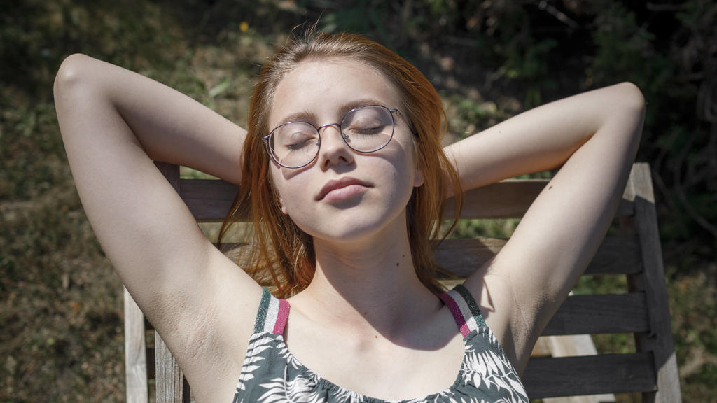 Portrait of young woman sunbathing on deckchair in garden model released Symbolfoto KMKF01346