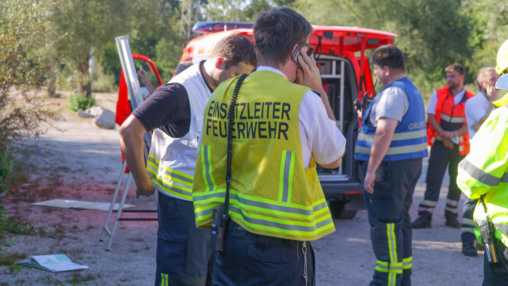 12.07.2020, Baden-Württemberg, Karlsruhe: Einsatzkräfte der Feuerwehr stehen mit Fahrzeugen auf einem Waldparkplatz. Ein Ultraleichtflugzeug mit zwei Männern ist am Sonntagabend in einen Wald bei Rheinstetten abgestürzt. Die zwei Männer, die mit dem