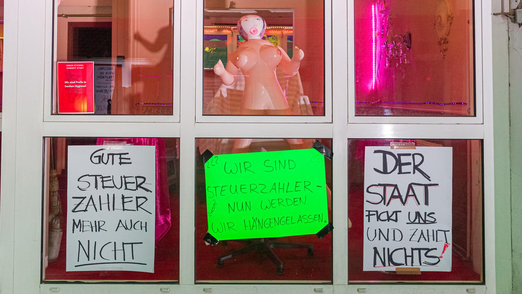 11.07.2020, Hamburg: An dem Fenster eines Bordells in der Herbertstraße hängen Transparente mit den Aufschriften «Gute Steuerzahler, mehr auch nicht», «Wir sind Steuerzahler, nun werden wir hängengelassen» und «Der Staat fickt uns und zahlt nichts!».