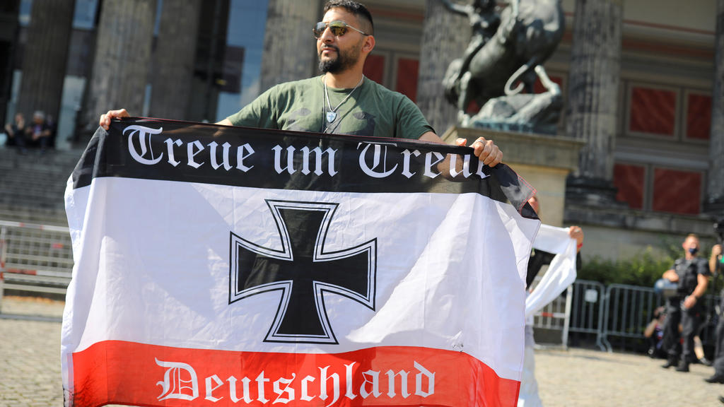 Attila Hildmann holds a flag reading "loyalty for loyalty" as activists protest against the government's restrictions following the coronavirus disease (COVID-19) outbreak, in Berlin, Germany, July 18, 2020. REUTERS/Hannibal Hanschke