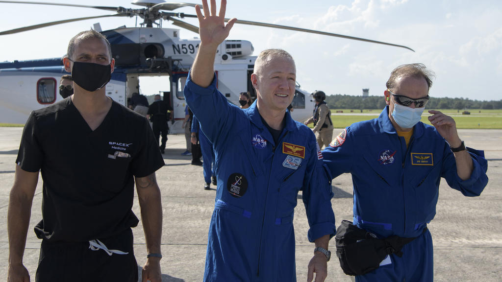 02.08.2020, USA, Pensacola: Dieses von der NASA zur Verfügung gestellte Foto zeigt den Astronauten Douglas Hurley (M) auf der Naval Air Station Pensacola, nachdem er mit der SpaceX-Kapsel «Endeavour» im Golf von Mexiko gelandet ist. Zwei Monate nach