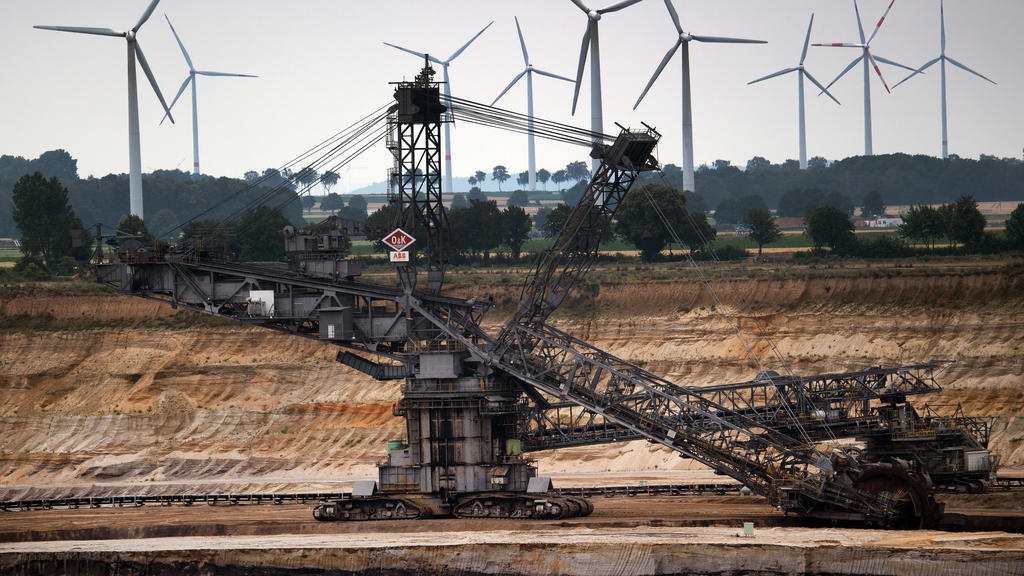 03.07.2020, Nordrhein-Westfalen, Jackerath: Hinter einem Schaufelradbagger im Braunkohletagebau Garzweiler drehen sich Windräder zur Stromerzeugung. Bundestag und Bundesrat wollen den schrittweisen Kohleausstieg in Deutschland bis spätestens 2038 bes