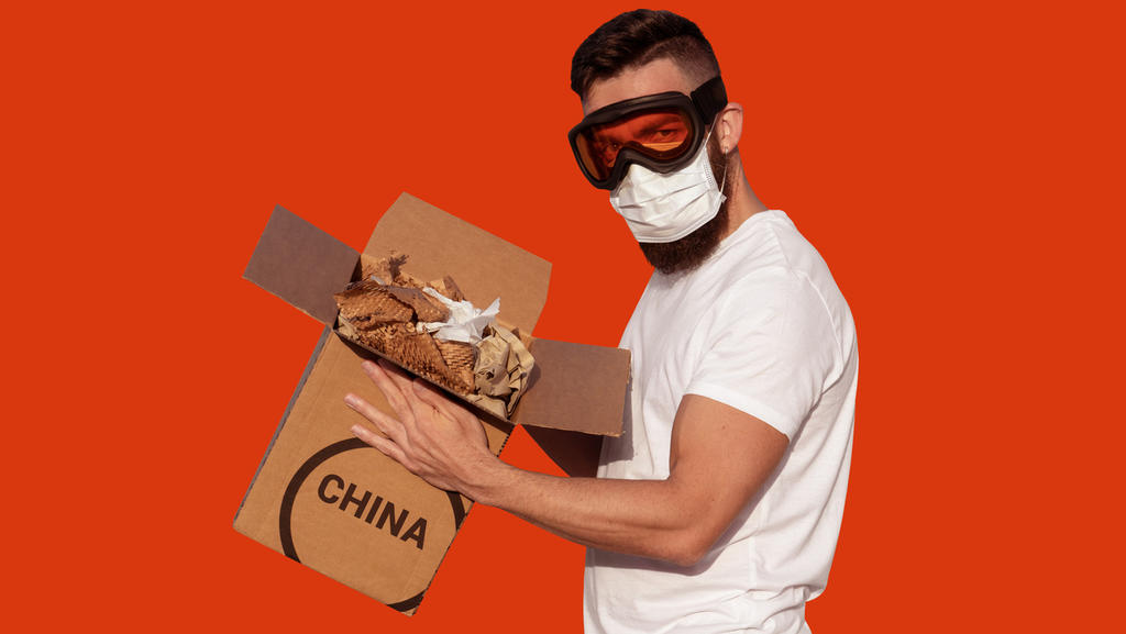 Mann mit Schutzbrille und chirurgischer Maske packt Pappkarton aus China aus