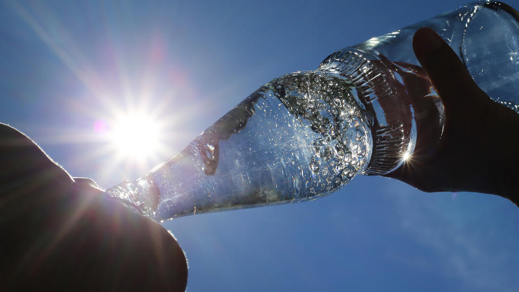 ARCHIV - 24.06.2019, Bayern, Kempten: Eine Frau trinkt im Sonnenschein aus einer Flasche sprudelndes Mineralwasser. (zu dpa: "Sex-Lust, Pickel und kalte Limo: Hitze-Mythen auf dem Prüfstand") Foto: Karl-Josef Hildenbrand/dpa +++ dpa-Bildfunk +++