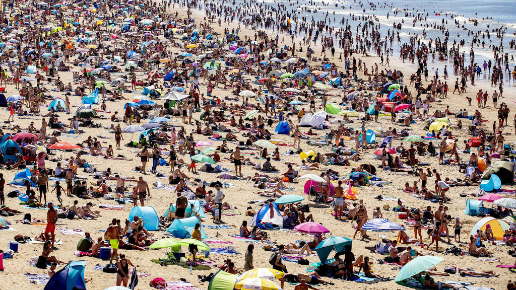 31.07.2020, Niederlande, Den Haag: Zahlreiche Menschen genießen das heiße Wetter am Strand von Scheveningen. Bei tropischen Temperaturen hat es einen Ansturm auf Strände in den Niederlanden gegeben. Die Bahngesellschaft NS warnte in einem ungewöhnlic