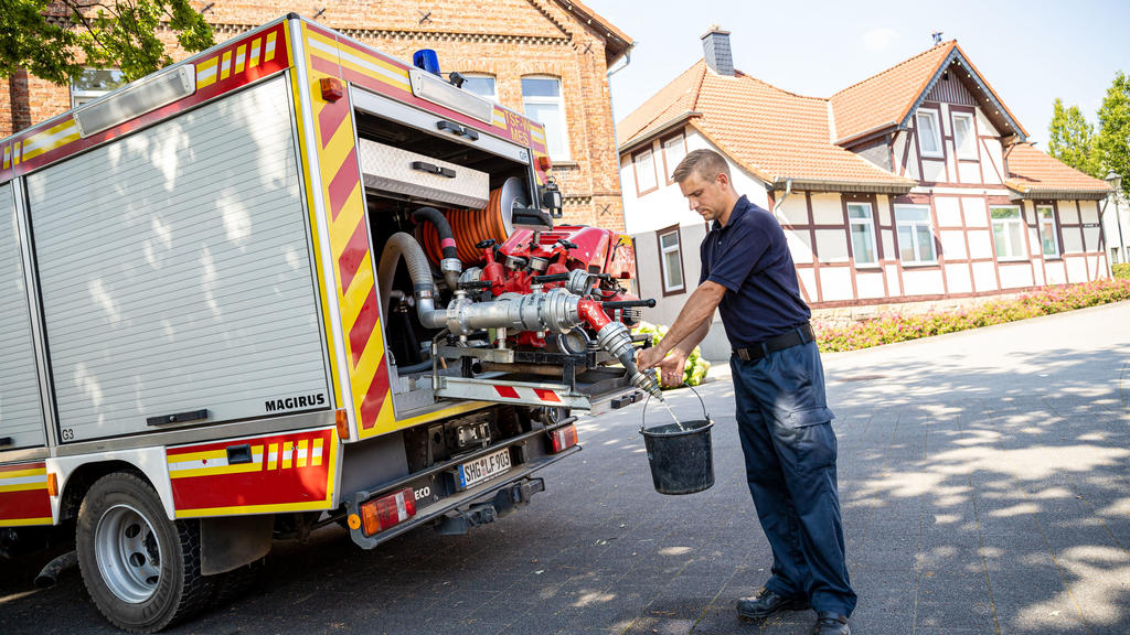 08.08.2020, Niedersachsen, Lauenau: Einsatzkräfte der Freiwilligen Feuerwehr Lauenau zapfen Löschwasser aus dem Tank eines ihrer Einsatzfahrzeuge. In der Gemeinde im Landkreis Schaumburg ist die Wasserversorgung nach warmen Tagen und während der Coro