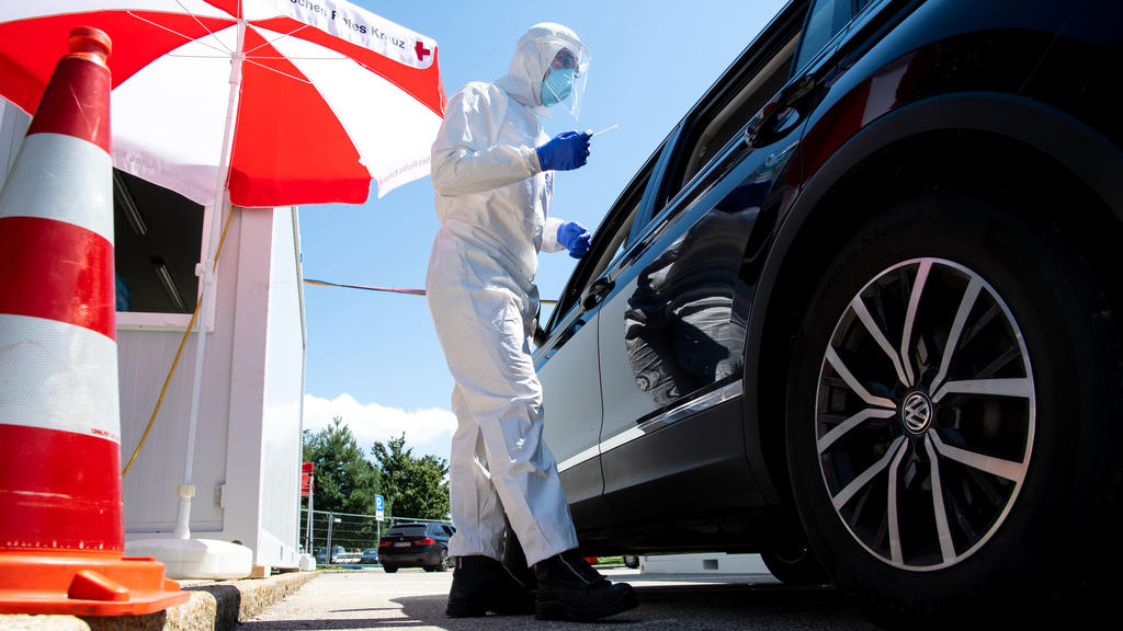 30.07.2020, Bayern, Bergen: Mitarbeiter vom Bayerischen Roten Kreuz nehmen an einem Corona-Testzentrum an der Autobahn 8 (A8) an der Rastanlage Hochfelln-Nord einen Abstrich. Mit Blick auf zuletzt steigende Corona-Infektionszahlen warnt die bayerisch