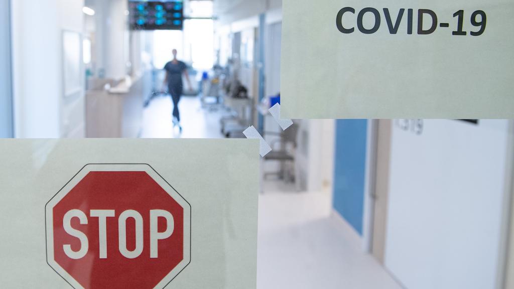 ARCHIV - 07.04.2020, Sachsen, Dresden: Eine Frau geht auf der Corona-Intensivstation im Universitätsklinikum Carl Gustav Carus Dresden hinter einer Glastür einen Gang entlang. (zu "Krankenhausgesellschaft sieht sich für zweite Corona-Welle gerüstet")