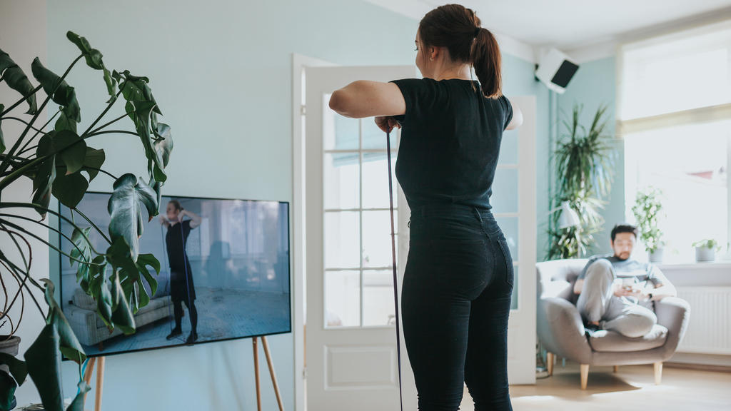 Frau trainiert vor dem Fernseher