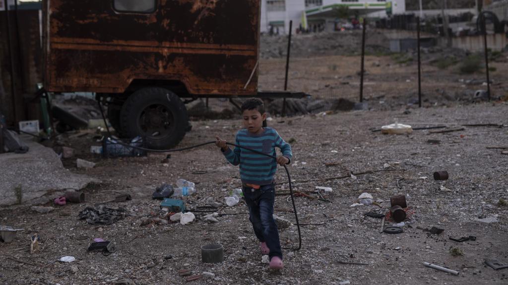 10.09.2020, Griechenland, Lesbos: Ein Junge spielt neben einem Fahrzeug vor dem Geflüchtetenlager Moria, nachdem mehrere Brände das Lager fast vollständig zerstört haben. Mehr als 24 Stunden nach Ausbruch der Feuer gab es immer noch keine offiziellen