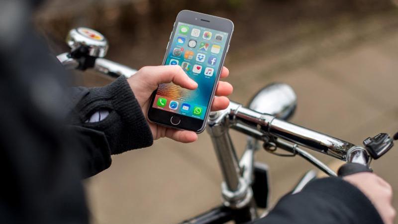 Eine junge Frau bedient beim Fahrradfahren ihr Smartphone