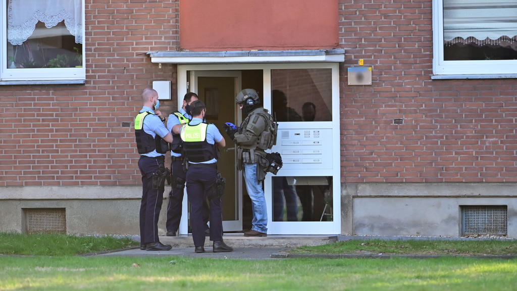 19.09.2020, Nordrhein-Westfalen, Krefeld: Polizei und ein SEK-Beamter stehen vor der Eingangstür eines Mehrfamilienhauses. In einer Wohnung im Haus hat sich möglicherweise ein Mann mit vier Kindern verschanzt. Die Polizei sei mit Spezialkräften im Ei