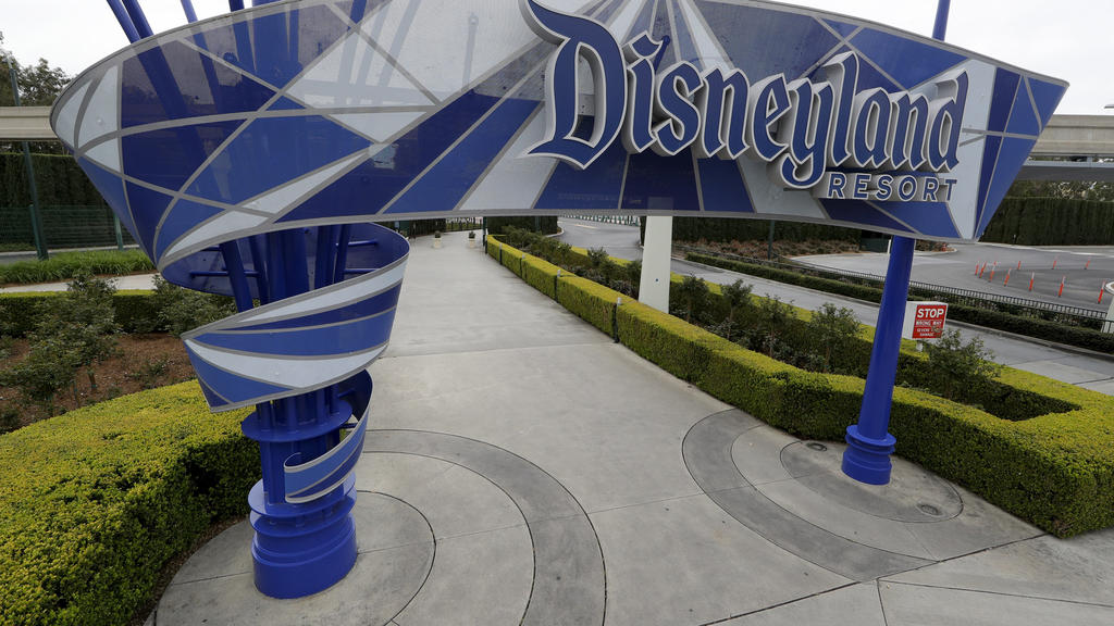 FILE - In this file photo taken Wednesday, March 18, 2020, one of the normally bustling entrances to the Disneyland resort is vacant due to the coronavirus closure in Anaheim, Calif. Squeezed by limits on attendance at its theme parks and other restr