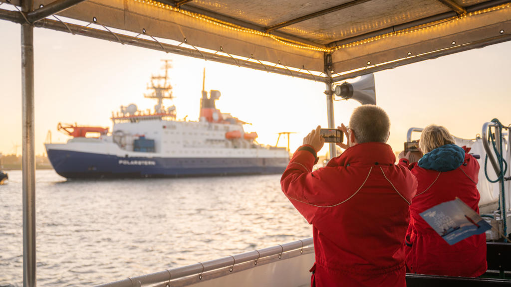12.10.2020, Bremen, Bremerhaven: Zwei Personen auf einem Schiff fotografieren die Rückkehr des Forschungsschiffs ·Polarstern·. Foto: Mohssen Assanimoghaddam/dpa +++ dpa-Bildfunk +++