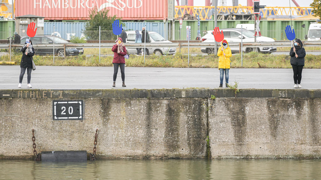 12.10.2020, Bremen, Bremerhaven: Vier Personen an einer Kaimauer winken während der Rückkehr des Forschungsschiffs ·Polarstern· mit blauen und roten Winkhänden. Foto: Mohssen Assanimoghaddam/dpa +++ dpa-Bildfunk +++