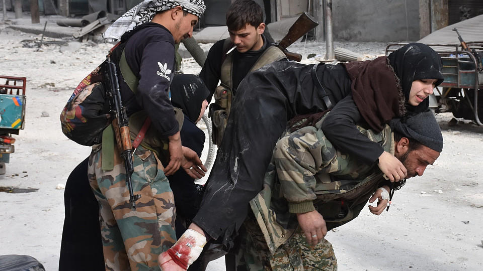 A Syrian pro-government fighter carries a wounded woman who was reportedly shot by rebel sniper while fleeing with her family Aleppo's eastern al-Salihin neighbourhood on December 12, 2016 after troops retook the area from rebel fighters. / AFP / GEO