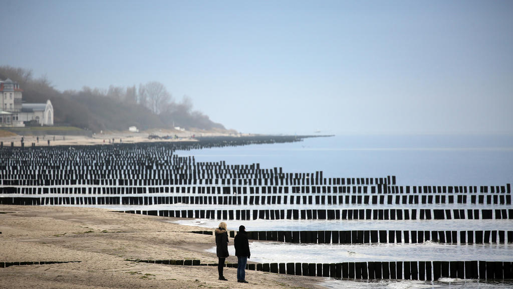 Am Ostseestrand von Kühlungsborn (Mecklenburg-Vorpommern) sind am 19.12.2016 Spaziergänger unterwegs. Trübes, aber ruhiges Wetter herrscht an der Küste. Foto: Bernd Wüstneck/dpa-Zentralbild/dpa +++(c) dpa - Bildfunk+++