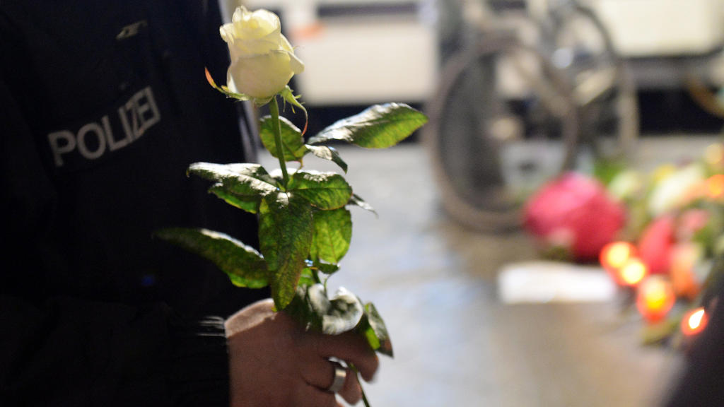 Ein Polizist hält am 20.12.2016 am Ort des Anschlags nahe der Gedächtniskirche eine weiße Rose in der Hand.