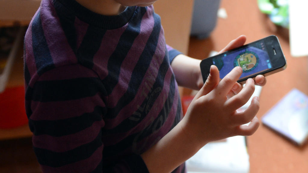 ARCHIV - ILLUSTRATION - Ein Junge spielt in seinem Kinderzimmer auf einem Smartphone ein Computerspiel, aufgenommen am 10.04.2012 in Berlin. Sieben von zehn Kindern im Krippen- und Kita-Alter nutzen Ärzten zufolge das Handy ihrer Eltern mehr als eine