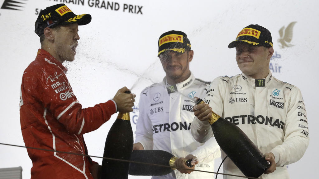 Motorsport: Formel-1-Weltmeisterschaft, Rennen, Grand Prix von Bahrain am 16.04.2017 in as-Sachir (Bahrain). Der Deutsche Sebastian Vettel vom Team Scuderia Ferrari (l) jubelt nach seinem Grand-Prix-Sieg. Neben ihm stehen der zweitplatzierte Brite Le
