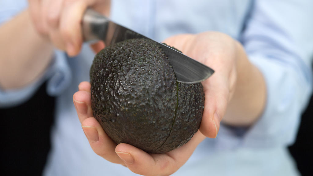 ARCHIV - Eine Frau schneidet am 15.02.2017 in Berlin mit einem Messer eine Avocado. (Zu doa «Mediziner warnt vor "Avocado-Hand"» vom 11.05.2017) Foto: Andrea Warnecke/dpa +++(c) dpa - Bildfunk+++