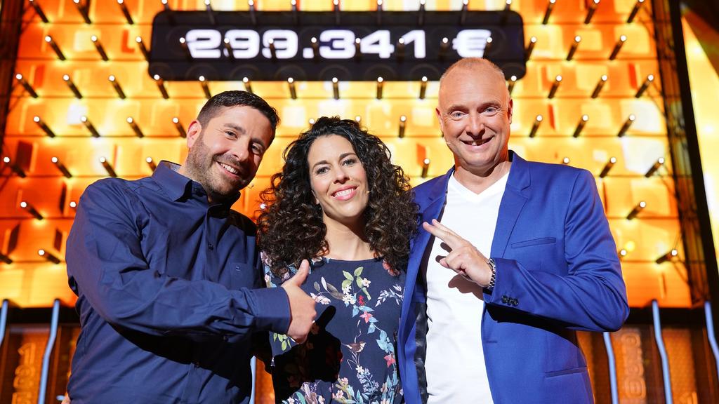 Moderator Frank Buschmann (l.) mit den Kandidaten Sabrina (37) und Basel (40) aus Meckenheim, die sich über ihren Gewinn von 299.341 Euro freuen.