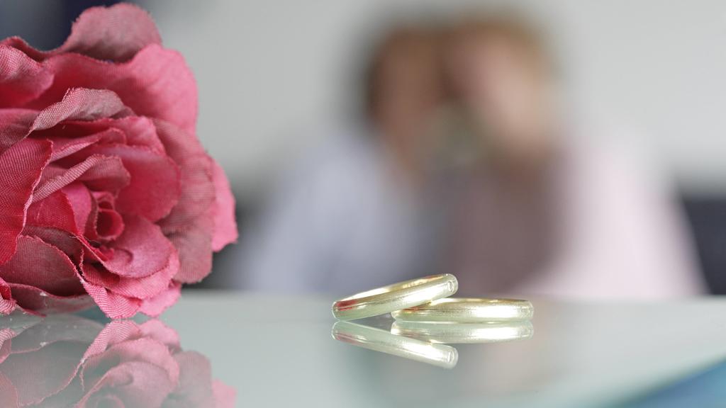 Eheringe mit Rose , im Hintergrund zwei Frauen . Radevormwald , 12.06.2006 , Radevormwald Deutschland PUBLICATIONxINxGERxSUIxAUTxONLY Copyright: xU.xGrabowskyxWedding rings with Rose in Background Two Women Radevormwald 12 06 2006 Radevormwald German