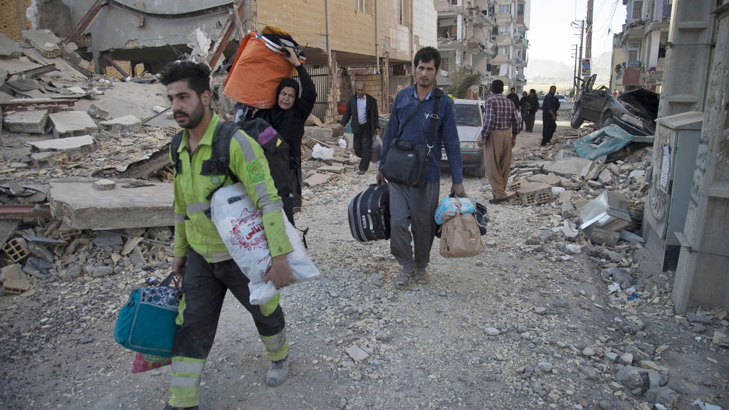 HANDOUT - Dieses von der Tasnim News Agency zur Verfügung gestellte Foto zeigt am 13.11.2017 in Sarpol-E-Zahab (Iran) Bewohner, die ihre Habseligkeiten tragen. Nach dem schweren Erdbeben in den südlichen Kurdengebieten in der Grenzregion zwischen dem