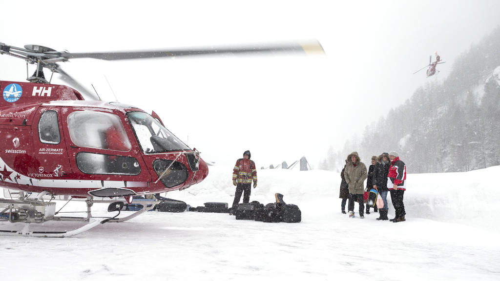 Touristen stehen mit ihrem Gepäck am 21.01.2018 auf dem Dach des Matterhorn Terminals in Täsch (Schweiz) um per Hubschrauber zum Wintersportort Zermatt zu fliegen. Zermatt in der Schweiz ist nach ergiebigen Schneefällen erneut weitgehend von der Auße