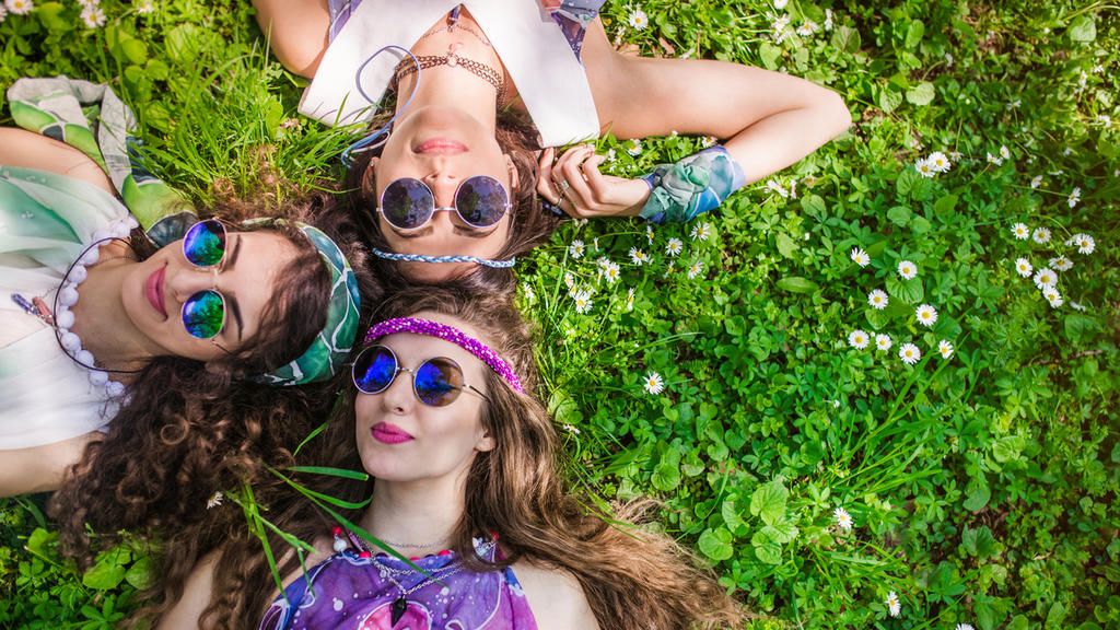 Beautiful girls of hippie laying on the grass and daisy flowers