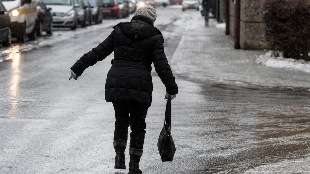 Eine Frau geht am 31.01.2017 in Straubing (Bayern) vorsichtig auf einer vereisten Straße. Der Deutsche Wetterdienst (DWD) warnt vor Glatteis in vielen bayerischen Landkreisen. Vor allem in der Oberpfalz, in Niederbayern und im bayerischen Wald müssen