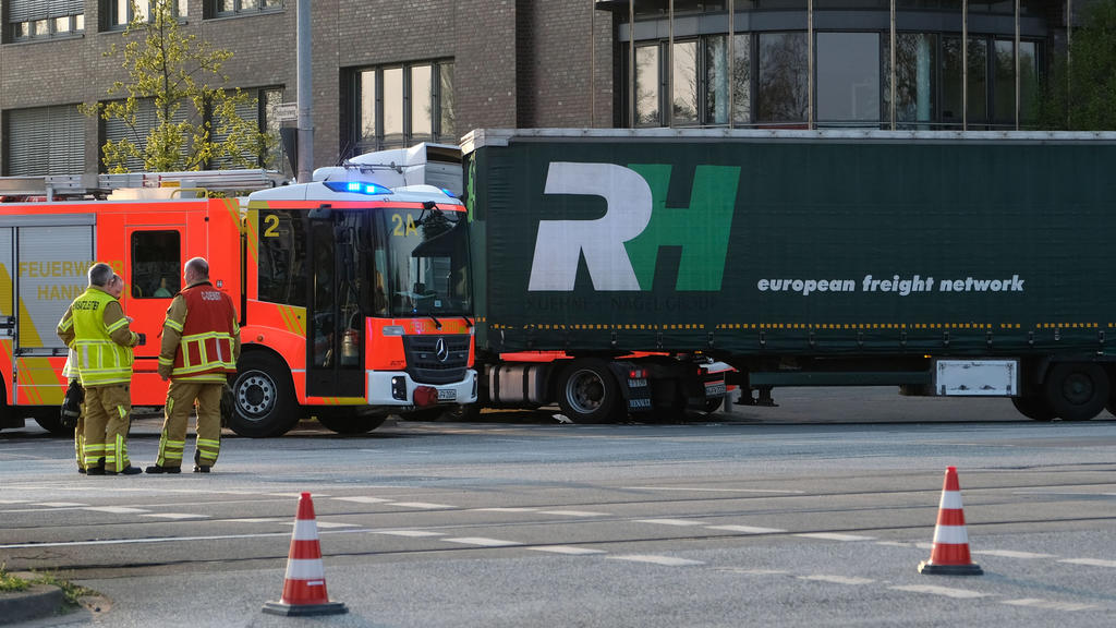 18.04.2018, Niedersachsen, Hannover: Feuerwehrmänner stehen an einer Unfallstelle neben einem Lastwagen. Ein Junge ist am Mittwoch von einem Lastwagen überrollt und getötet worden. Das Kind war offenbar mit einem Fahrrad an einer Kreuzung unterwegs,